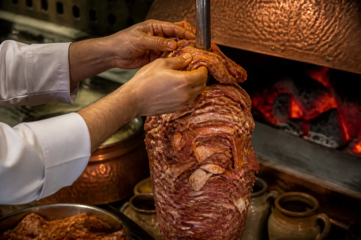 Broche de kebab en cours de montage, couches de viande empilées sur l’axe